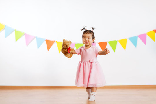 childhood, people and celebration concept - happy baby girl with teddy bear toy on birthday party