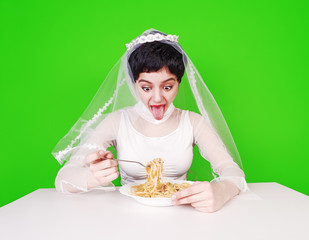 hungry frets in wedding attire eating pasta sitting at a table on a green background