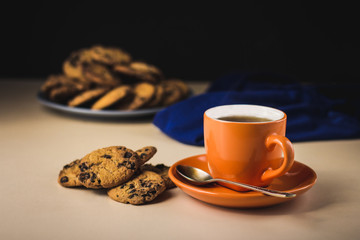 Background with a cup of hot tea and homemade cookies with chocolate. Orange cup of tea with cookies.