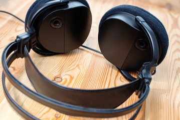 Black big full size or over-ear headphones on a wooden background. Circumaural headphones