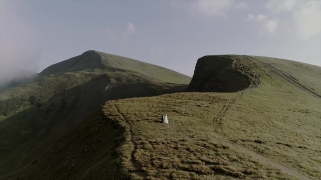 beautiful wedding couple walks in mountains aerial view 4k