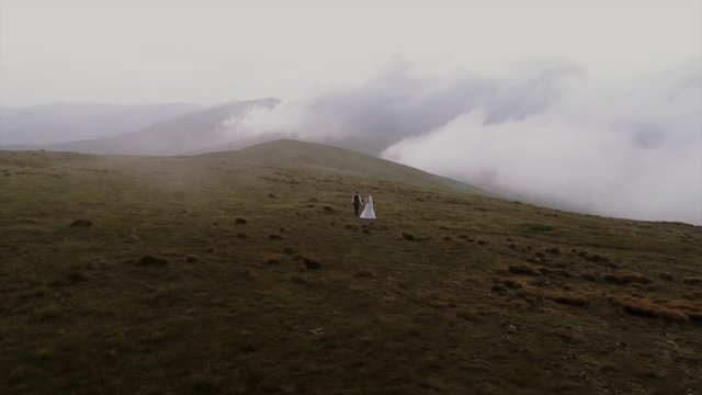 beautiful wedding couple walks in mountains aerial view 4k