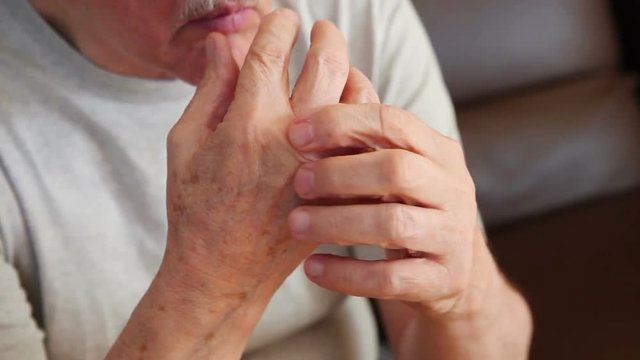 An older man tries to ease the pain in his hand