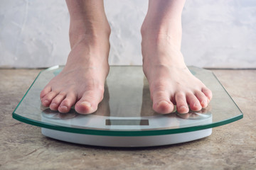 Female feet standing on electronic scales for weight control on light background. Concept of sports training, diets