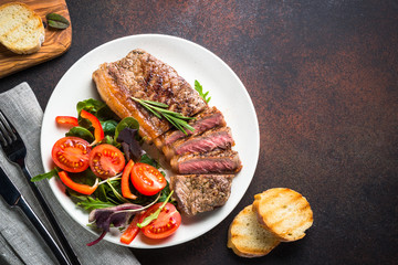 Grilled beef striploin steak with fresh salad top view.