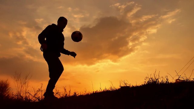man coins a ball European the football soccer freestyle silhouette at sunset sunlight. man beats chasing ball football outdoors world championship lifestyle
