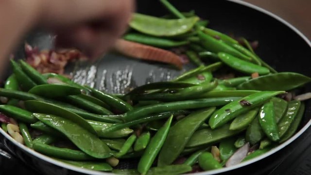 Sauteeing string beans and lima beans in close up.