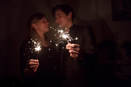 Young couple using sparklers at party