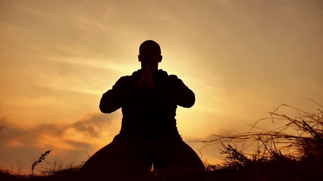 silhouette of a male monk engaged in meditation at sunset sunlight. Buddhist prays at sunset healthy way of lifestyle life nature