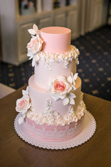 Obraz na płótnie Canvas Beautiful elegant four tiered pink wedding cake decorated with roses flowers. Concept floral from sugar mastic