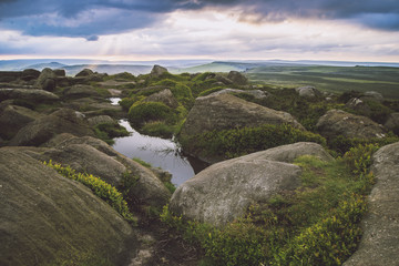 Sun bursting through clouds over rocky green landscape