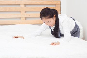 Attractive Beautiful Asian woman maid cleaning and arrange blanket on bed in bedroom,Service Cleaning Concept