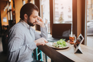 Busy man is in a hurry, he does not have time, he is going to eating and working. Worker eating, drinking coffee, talking on the phone, at the same time. Businessman doing multiple tasks. Multitasking