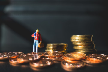 Miniature people, man standing on stack coins using as business concept