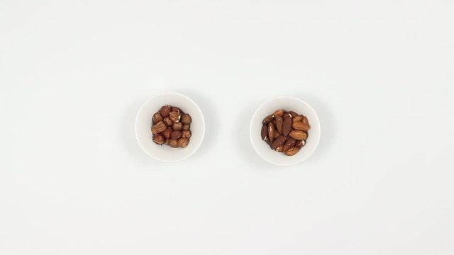 A woman and a man are eating nuts at a table. Hazelnuts and almon. Top view