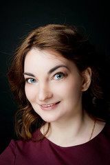 Naklejka premium A brunette girl with a smile on her face against a black background. Studio portrait of a woman.