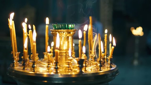 atmosphere of the Christian church, many candles burn, slow-motion shooting, smooth movement, camera slide, icons and religion, concept sacred rituals, wedding, baptism, communion, prayers to God