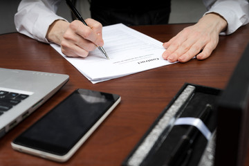 A businessman puts his signature on the contract. Copy space.