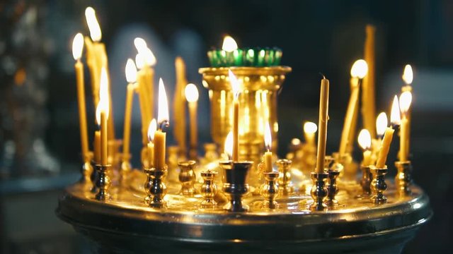 atmosphere of the Christian church, many candles burn, slow-motion shooting, smooth movement, camera slide, icons and religion, concept sacred rituals, wedding, baptism, communion, prayers to God