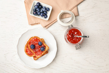 Toasts with jam and berries on wooden background, top view
