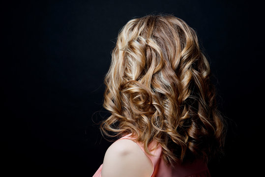 Hairstyle short curls back view of turning the head to the left on a black background. Female professional hairstyle.