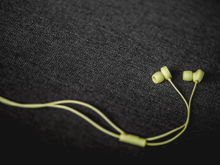 Yellow earbuds on the dark brown sofa background.