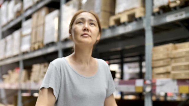4K Slow motion Asian woman rides shopping cart through the warehouse, Choosing new furniture, Tilt down