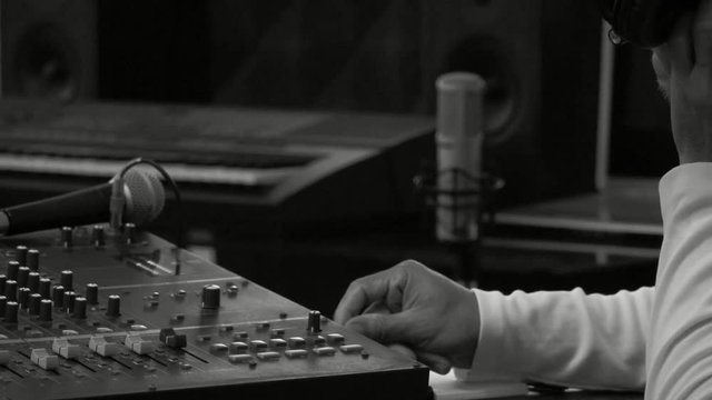 Music producer working in recording studio.
Male sound engineer producer holding headphone snapping and OK finger to colleagues ,HD slow motion monochrome. 