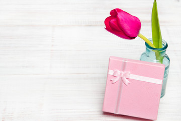 Pink tulip and gift on white wooden background, copy space