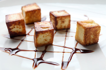 Cubes of typical brazilian ("queijo coalho") crumbled cheese with cane molasses on white background.