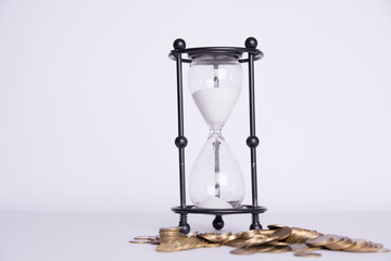Spilled money and hourglass on a white background