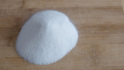 Pile of white granulated sugar on a wood cutting board