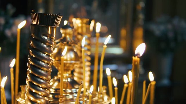 atmosphere of the Christian church, many candles burn, slow-motion shooting, smooth movement, camera slide, icons and religion, concept sacred rituals, wedding, baptism, communion, prayers to God