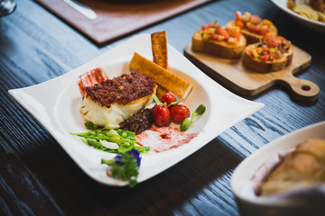 Baked Cod fish with sauce, pan grilled baby vegetables, pea and tomato served with bread sticks.