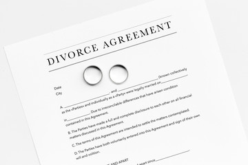 Divorce agreement. Wedding ring on document on white background top view