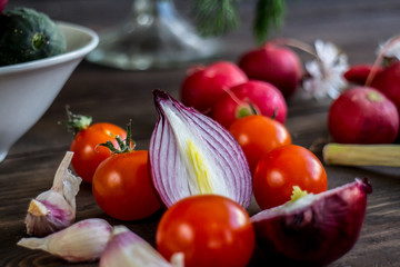 Tomatoes, cucumbers, onions, radish, garlic, pepper, dill, garlic and mushrooms on a dark wooden background.
