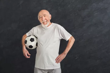 Tuinposter Senior man with soccer ball showing thumb up © Prostock-studio