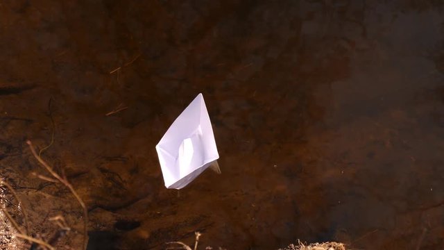 little white paper boat is floating on the water.