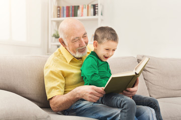 Senior man reading book for his grandchild