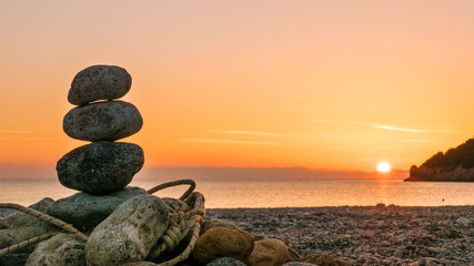 stone stack fireplace with rope on beach at sunrise