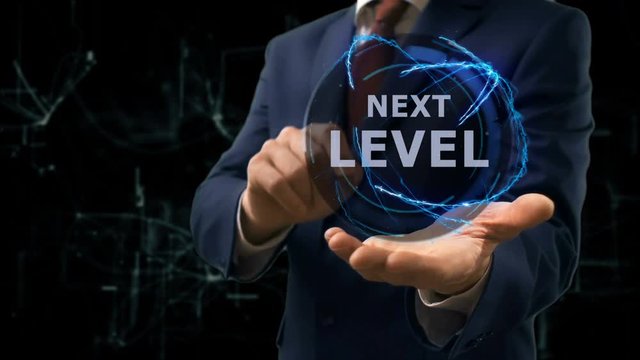 Businessman shows concept hologram Next level on his hand. Man in business suit with future technology screen and modern cosmic background