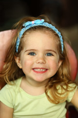 Close up portrait of a toddler girl with a very toothy smile