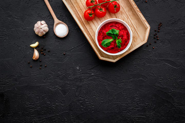 Ingredients for tomato sauce. Cherry tomatoes, garlic, green basil, black pepper, salt in spoon on black background top view space for text