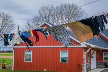 Outdoor view of clothes of Amish drying in the sun and air after laundry with a wooden red house background in Lancaster