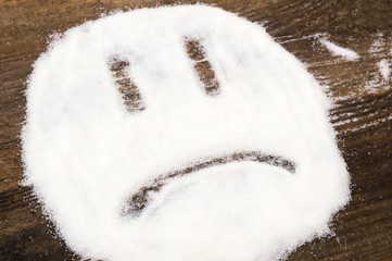 Face of a sad smiley made with granulated sugar. The picture illustrates the harm of eating sugar...