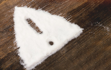 Sign of warning attention made of granulated sugar. A conceptual photo illustrating the harm from consuming white refined sugar and products containing it