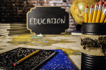 decorative car full of pencils and note books on world map with globe stack of books and small chalk board with education written on it