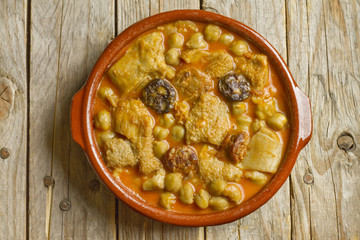Spanish callos with chickpeas on an earthenware bowl on a wooden table