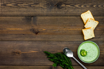Natural, organic food. Green vegetable soup-puree in bowl ready to eat served with rusks on dark...