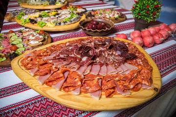 Meat assortment of sausage, smoked meat, on a wooden board on wedding table